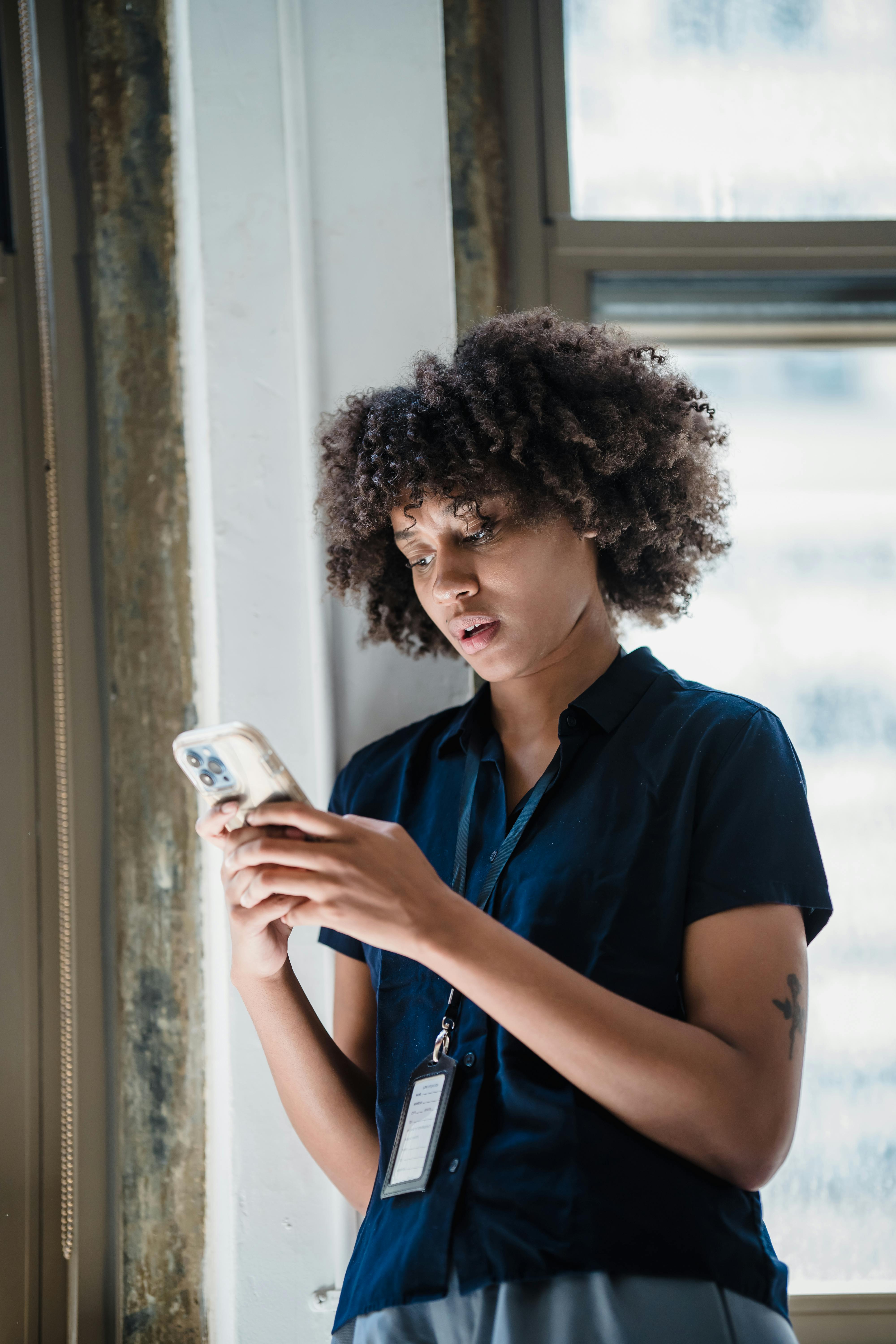 Young woman engaging with smartphone in modern office setting.
