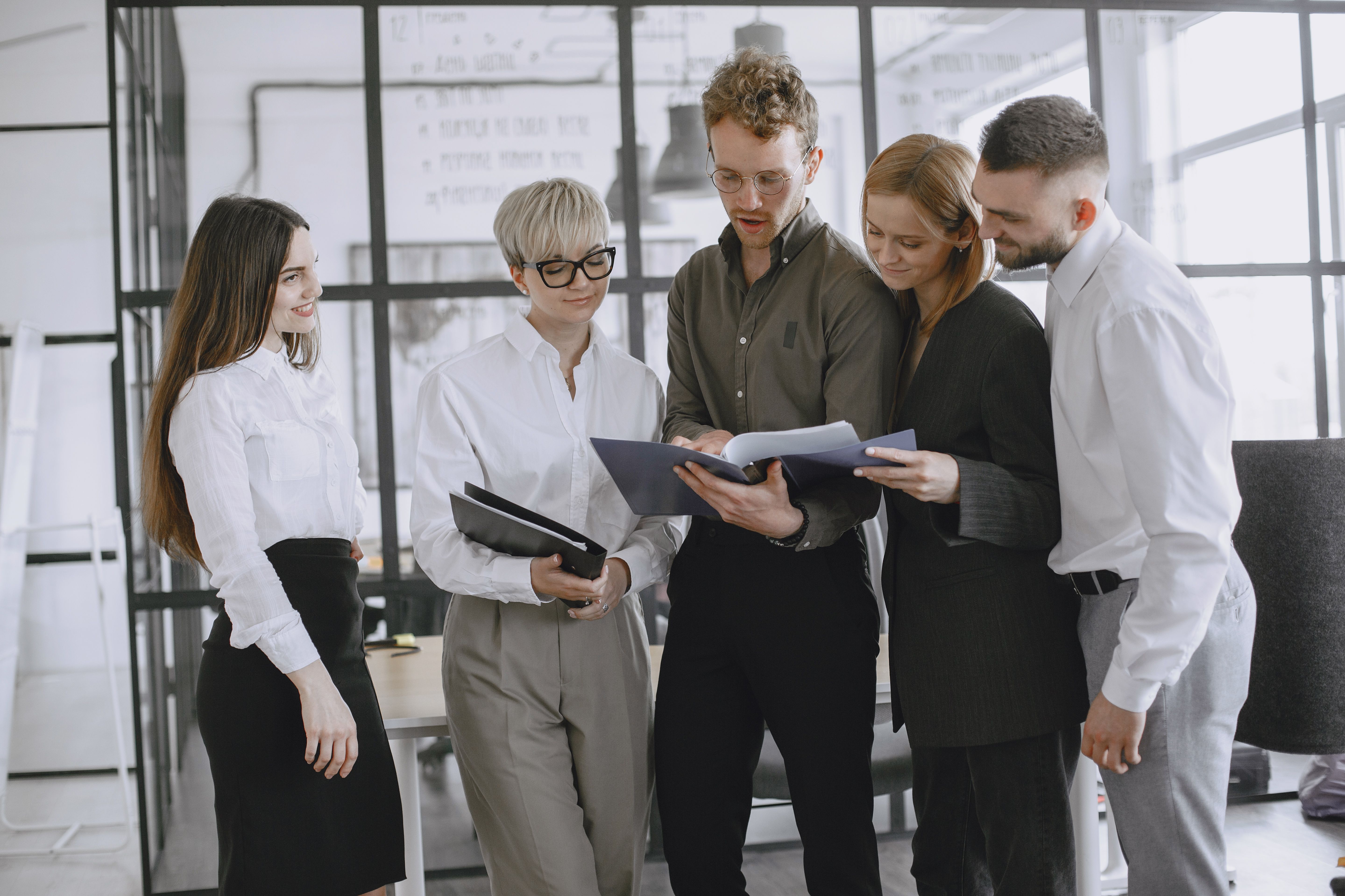 A diverse group of professionals collaborating and discussing documents in a modern office space.